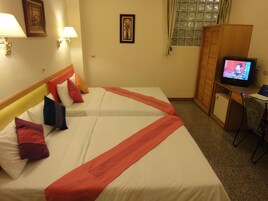 A hotel room with two beds, a television, a desk, and a wardrobe.