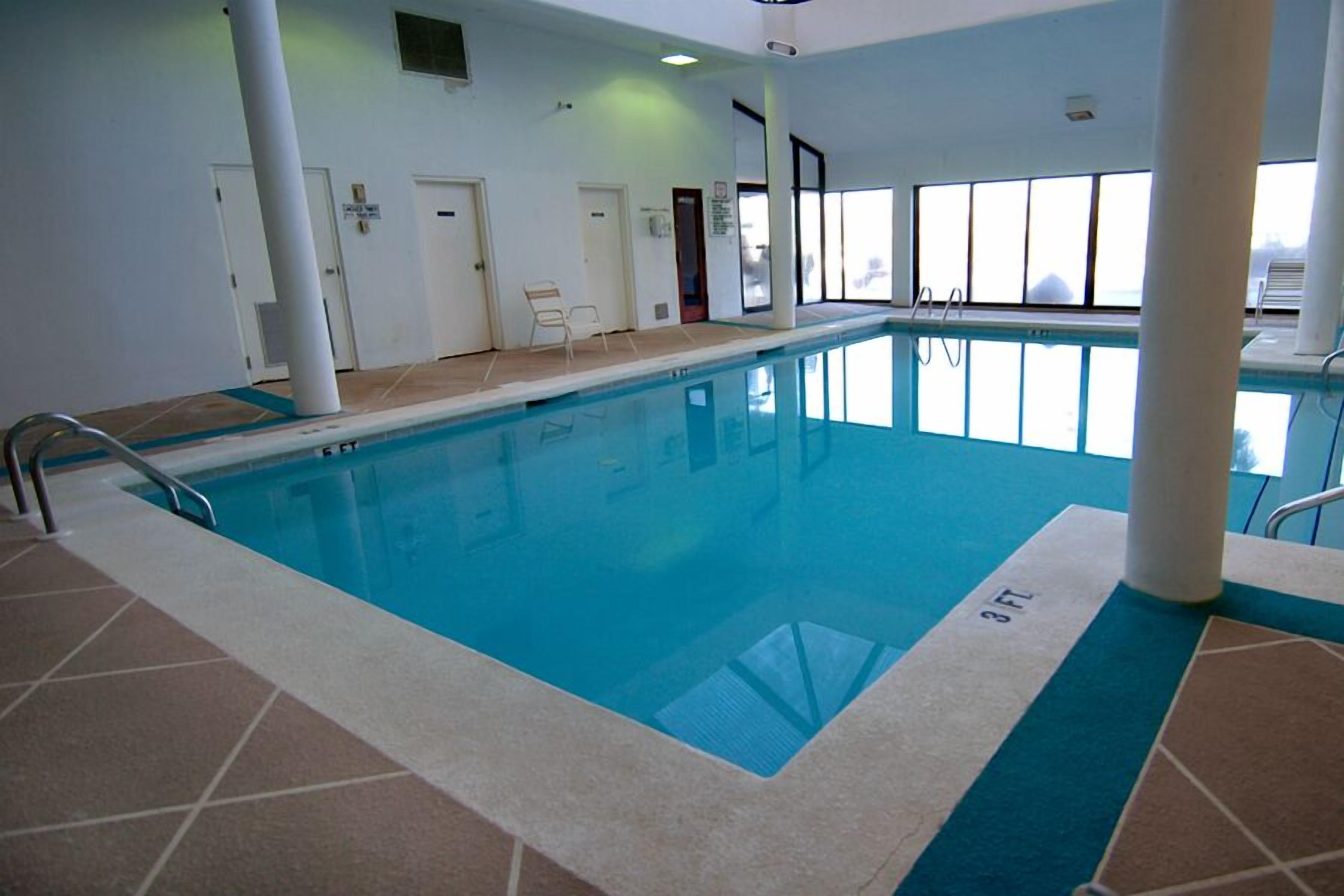 An indoor swimming pool with clear blue water, tiled flooring, and a 3 FT depth marker.