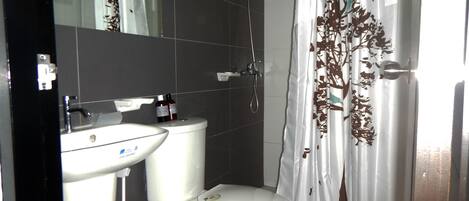 A bathroom with a toilet, sink, and shower.