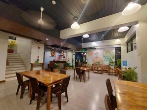 Un restaurante con mesas y sillas de madera, una escalera y un mural en la pared.