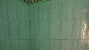 Een badkamer met een toilet, een rode emmer en een wastafel.