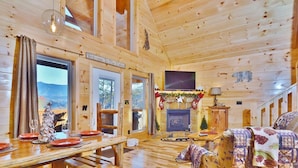Ein Holzblockhaus-Interieur mit Essbereich, Kamin und gemütlichem Sitzbereich.