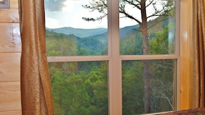 Ein Zimmer mit einem großen Fenster und Blick auf eine bewaldete Landschaft.