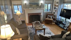 Un salon avec une cheminée, un canapé, une table basse et un téléviseur.
