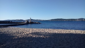 A sandy beach with a lighthouse and rocky pier extending into the sea. - Villa by the beach and with panoramic view on St Tropez (Grimaud)