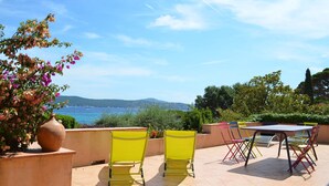 An outdoor patio with a table and chairs, overlooking a scenic view of the sea and hills. - Villa by the beach and with panoramic view on St Tropez (Grimaud)