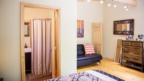 Een kamer met een douche, een bank, een dressoir en een spiegel.