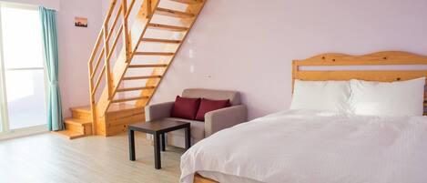 A bedroom with a wooden bed, a sofa, a small table, and a wooden staircase.