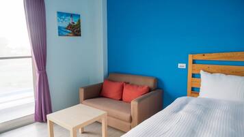 A room with a bed, a sofa, a small table, and a painting on the wall.