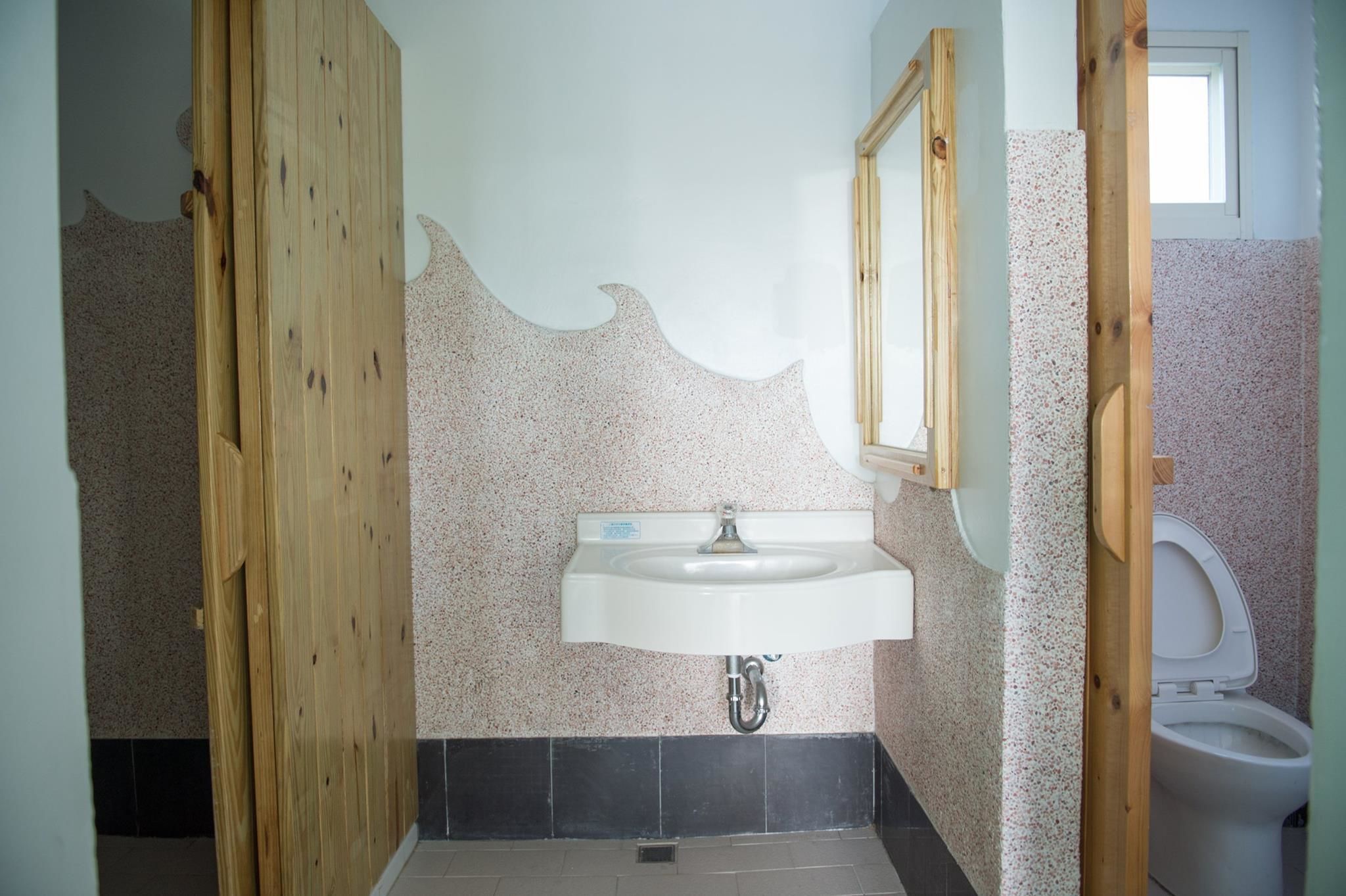 A bathroom with a white sink, wooden door, and a tiled wall with a speckled pattern.