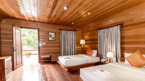 A wooden cabin room with two beds, a small table with a lamp, and a door leading to an outdoor area. - Angkor Heart Village (Siem Reap)
