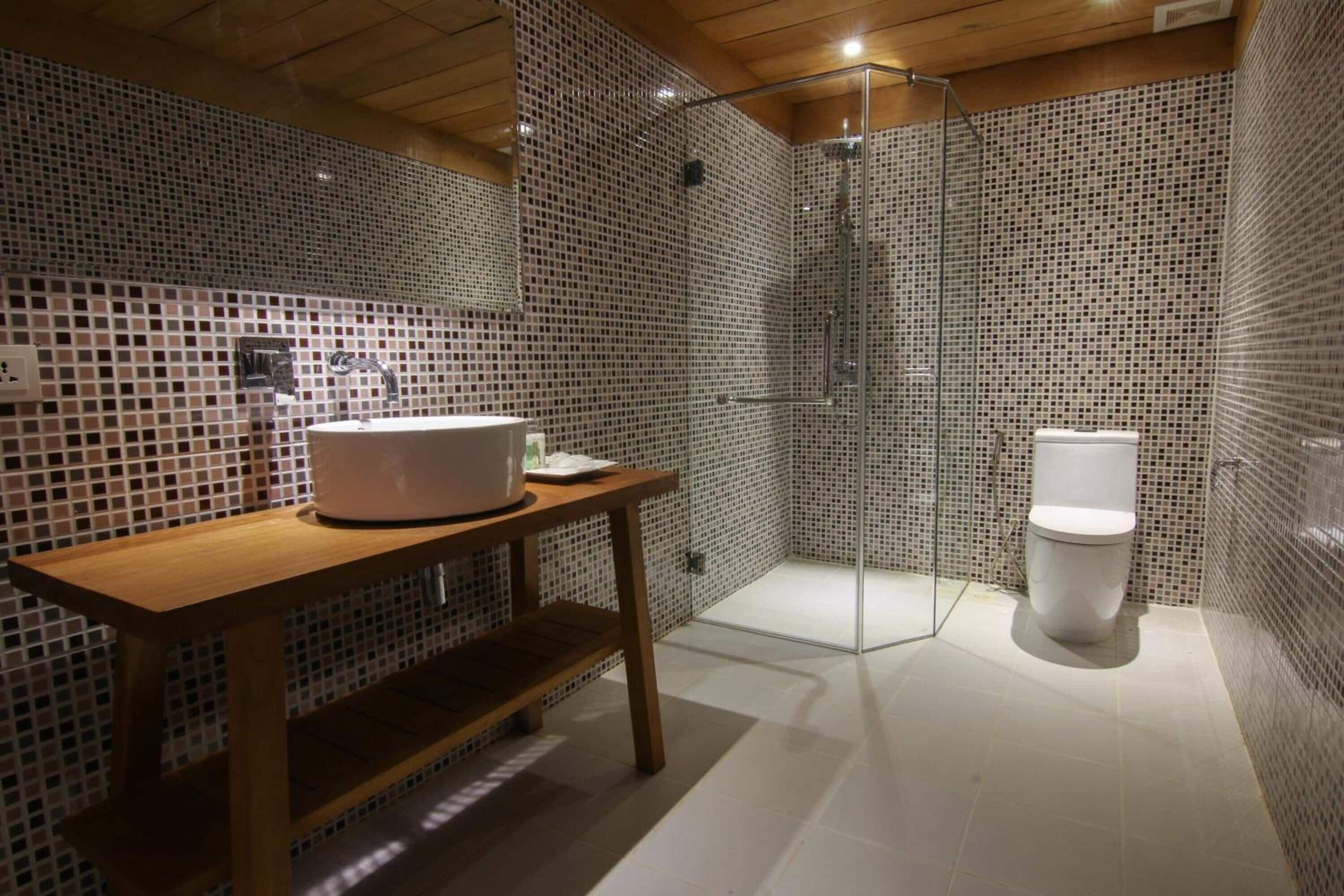 Une salle de bain moderne avec un meuble-lavabo en bois, une cabine de douche en verre et des toilettes blanches.