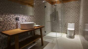 Une salle de bain moderne avec un meuble-lavabo en bois, une cabine de douche en verre et des toilettes blanches.