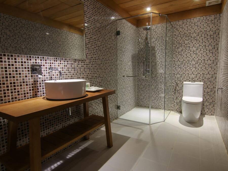 Une salle de bain moderne avec un meuble-lavabo en bois, une cabine de douche en verre et des toilettes blanches.
