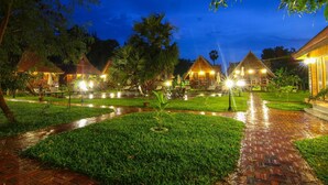 A well-lit outdoor area with pathways, small trees, and a brick walkway. - Angkor Heart Village (Siem Reap)