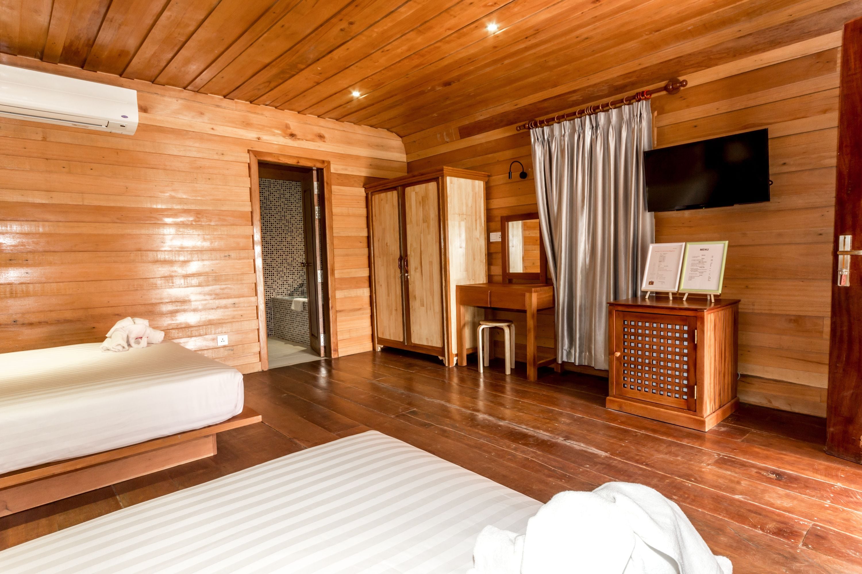 Une chambre dans un chalet en bois, comprenant un lit, un bureau, une télévision et un petit placard.