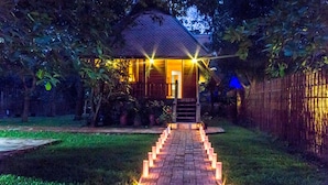 A house with a brick pathway leading to the entrance, surrounded by greenery and a bamboo fence. - Angkor Heart Village (Siem Reap)