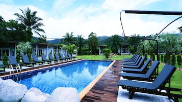 Una piscina al aire libre, sillones reclinables de piscina