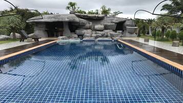 Una piscina al aire libre, sillones reclinables de piscina