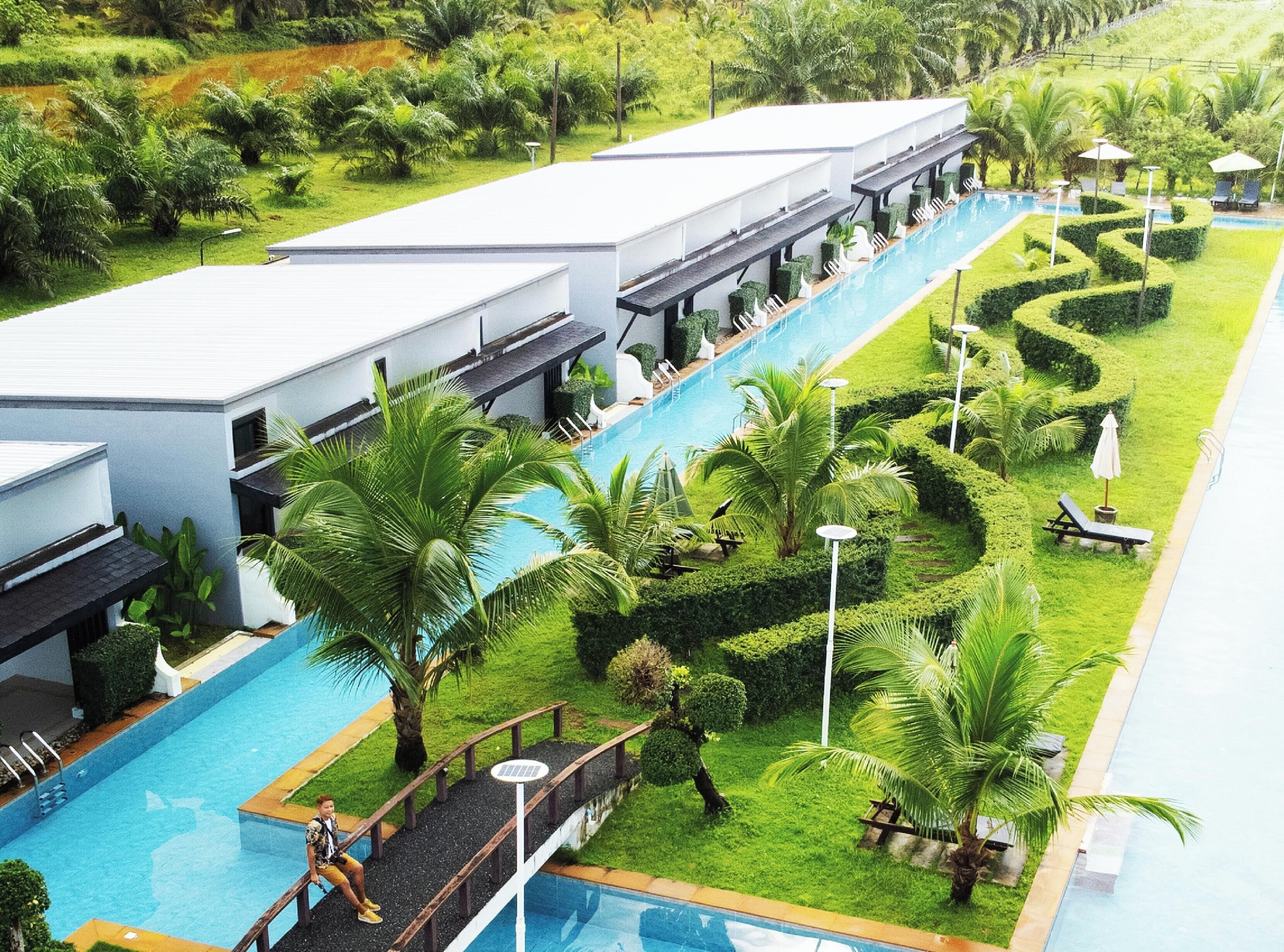 Un resort con piscina, sillas de descanso y palmeras.