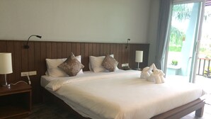 A large bed with white linens, two bedside tables with lamps, and a view of the outdoors through a sliding door. - Khaolak Mountain View (Takua Pa)
