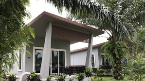 A modern house with a covered porch, a number 27 sign, and a well-maintained garden with various plants and a palm tree. - Khaolak Mountain View (Takua Pa)