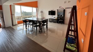 A modern room with a dining table, chairs, a TV, and a wardrobe. - Mangyi Inn (Hengchun)