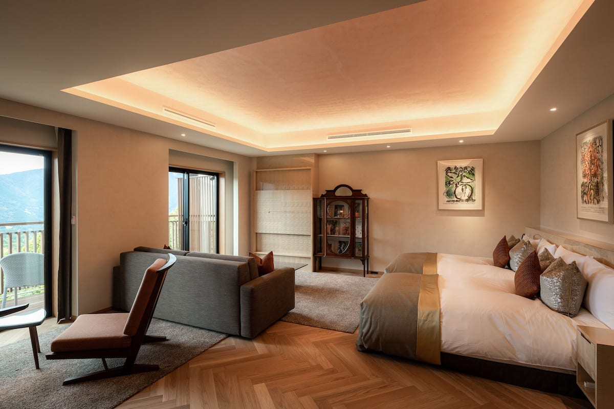 Ein modernes Hotelzimmer mit einem großen Bett, einer Couch, einem Sessel und Holzböden.