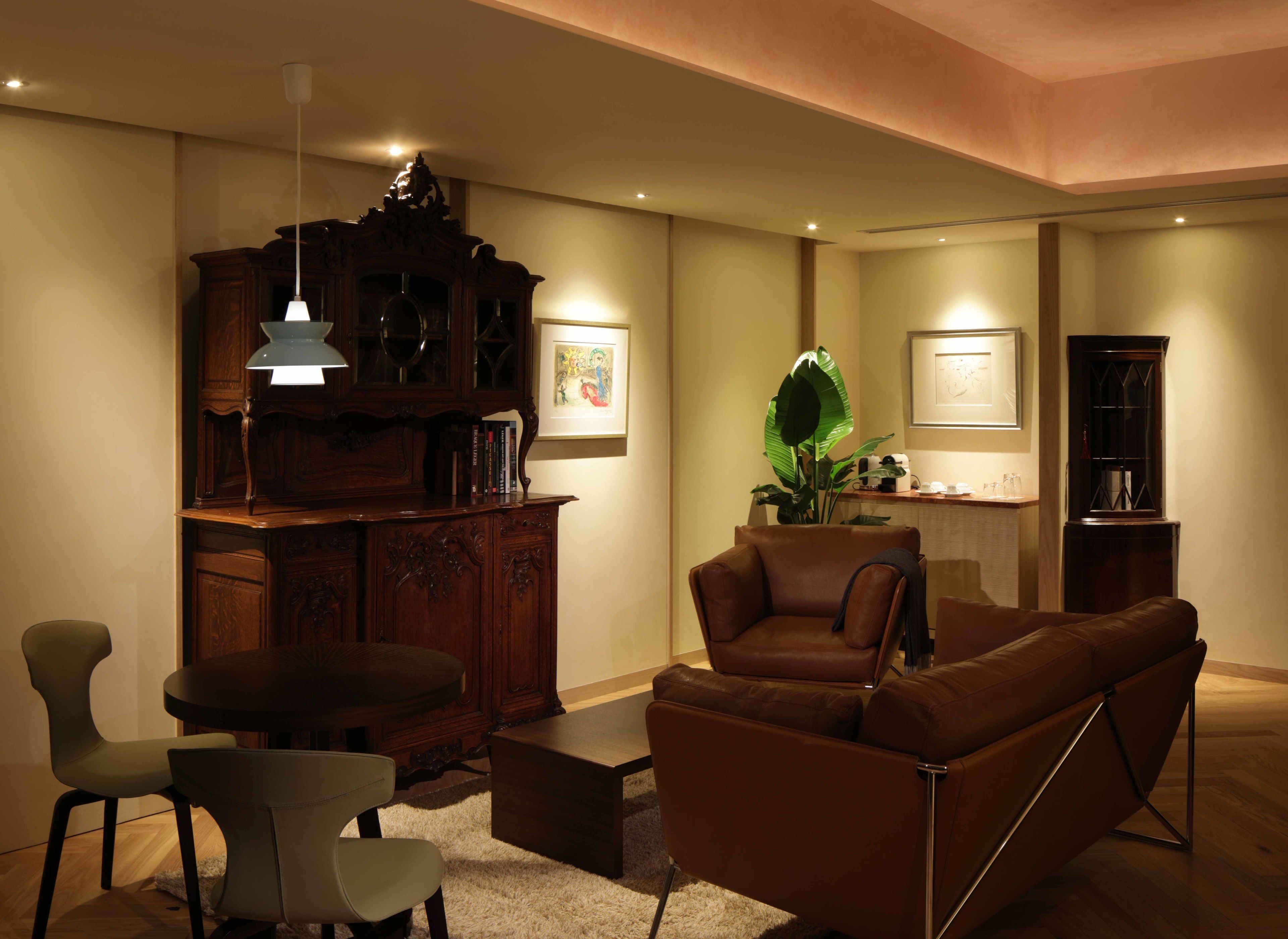 Una sala moderna con un sofá de cuero marrón, un mueble de madera y un comedor con una mesa y sillas.