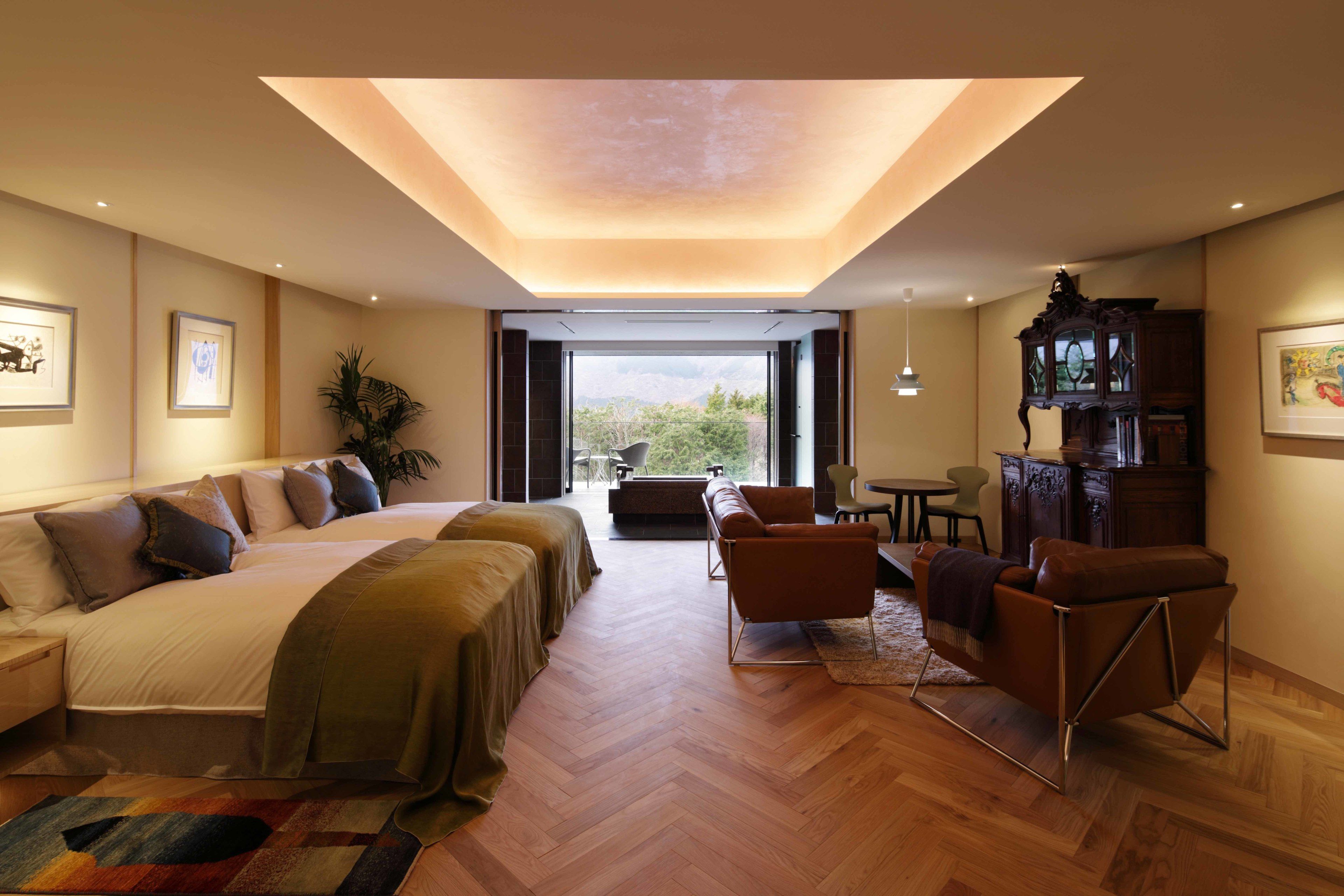 Una habitación de hotel moderna con una cama grande, un sofá, una mesa de centro y un escritorio. Una ventana amplia ofrece vistas al exterior.