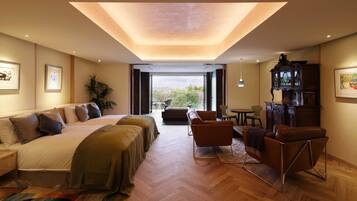 Una habitación de hotel moderna con una cama grande, un sofá, una mesa de centro y un escritorio. Una ventana amplia ofrece vistas al exterior.