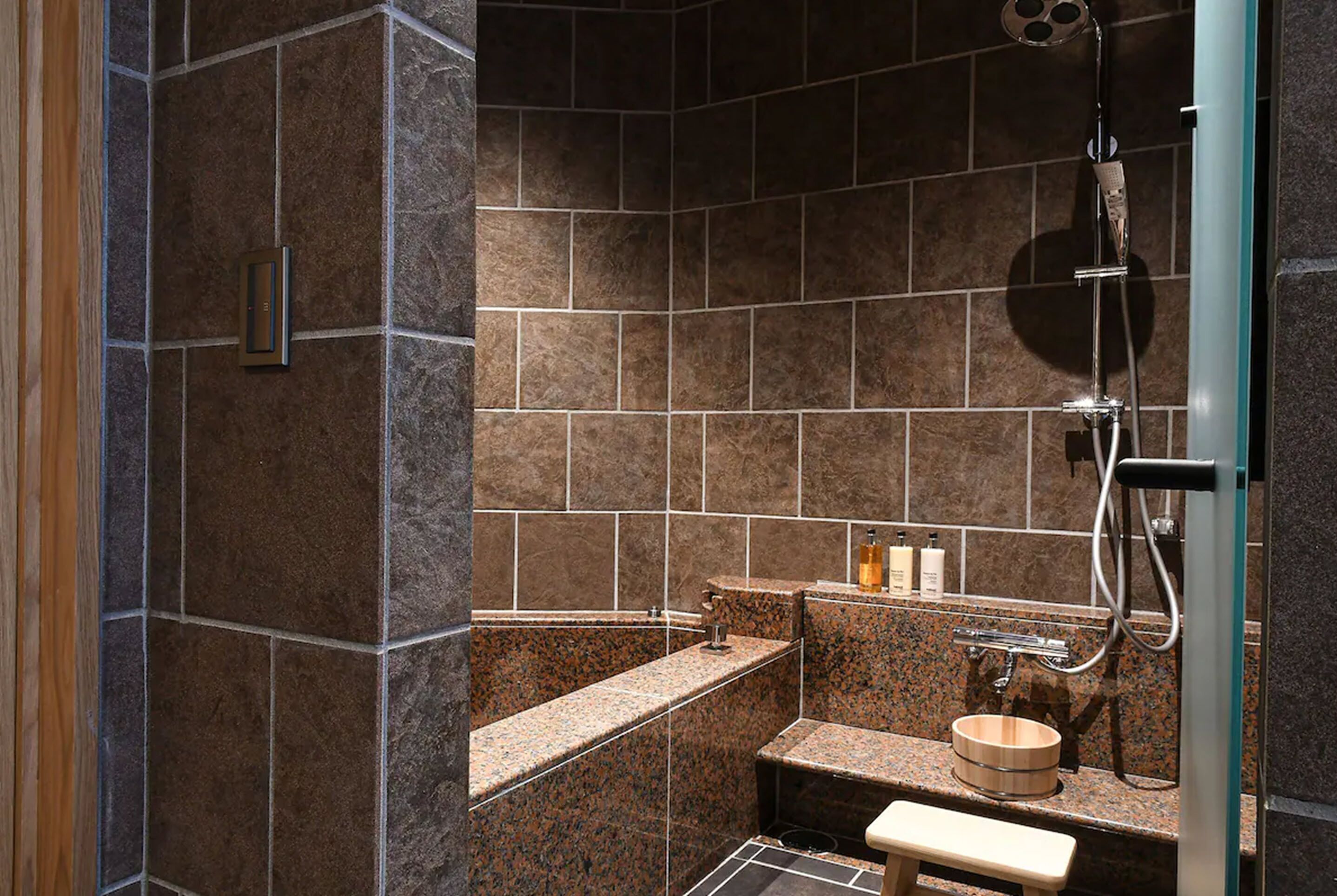 A bathroom with a shower, a sink, and a bench.