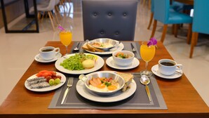 Een ontbijttafel gedekt met borden met eieren, toast en fruit, samen met kopjes koffie en sinaasappelsap.