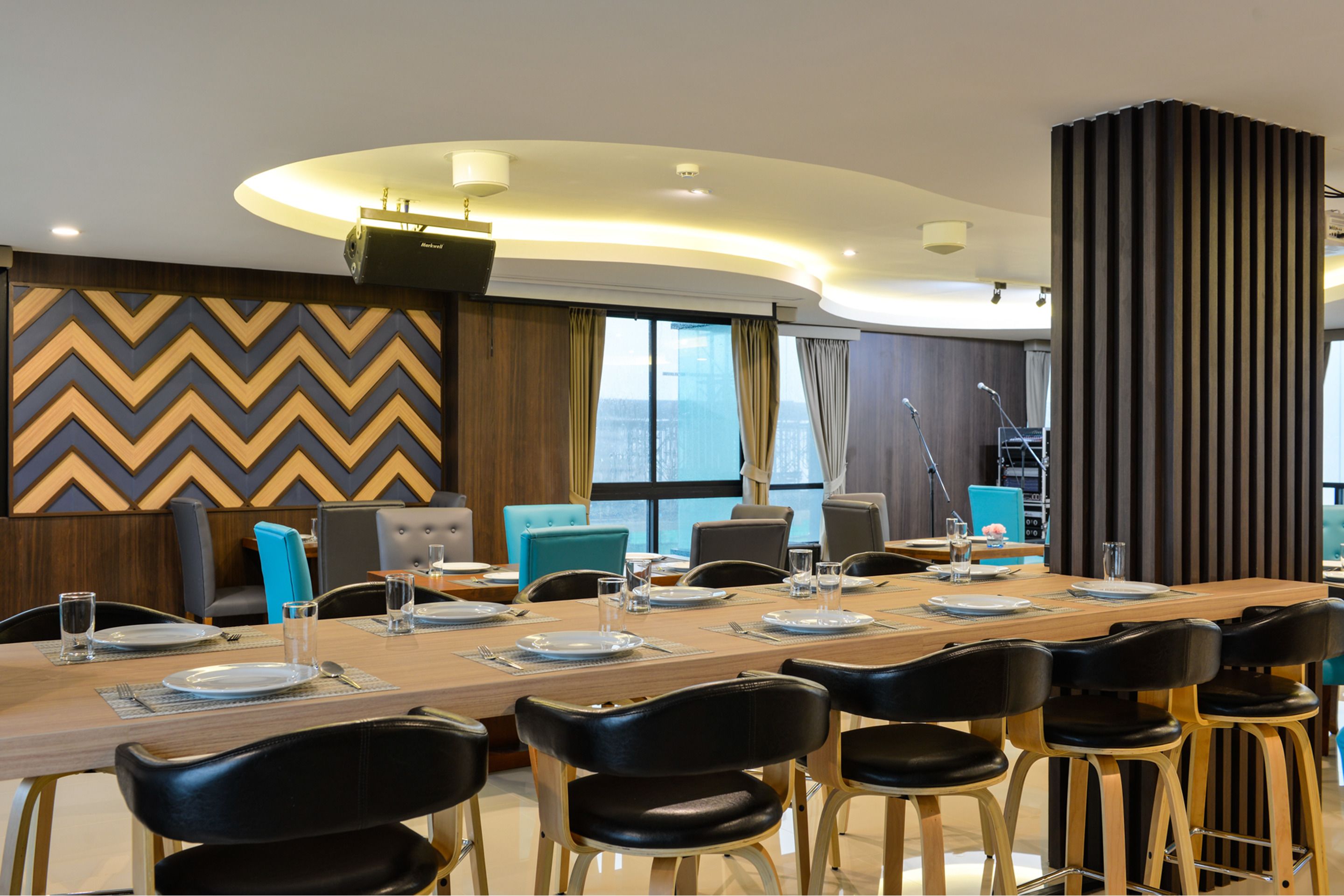 A modern conference room with a long table set for a meeting, equipped with microphones and a podium.