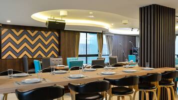 A modern conference room with a long table set for a meeting, equipped with microphones and a podium.