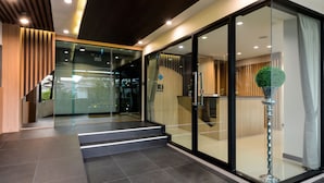 Een moderne hotellobby met glazen entree, een receptiebalie en een trap naar de verdiepingen.