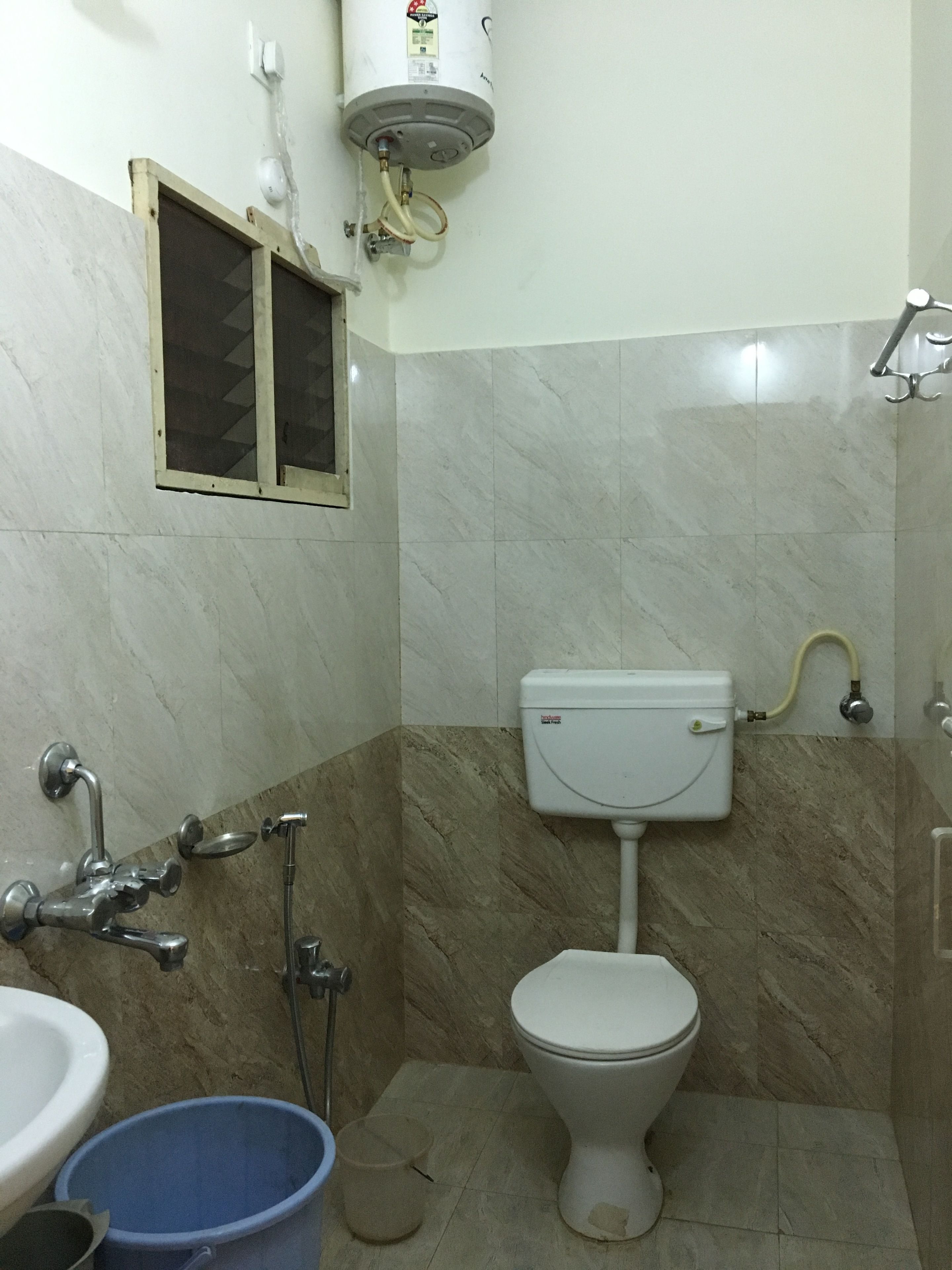 A bathroom with a toilet, sink, shower, and a water heater.