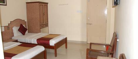 A hotel room with two wooden beds, a wooden chair, a cabinet, and a door with a lock.