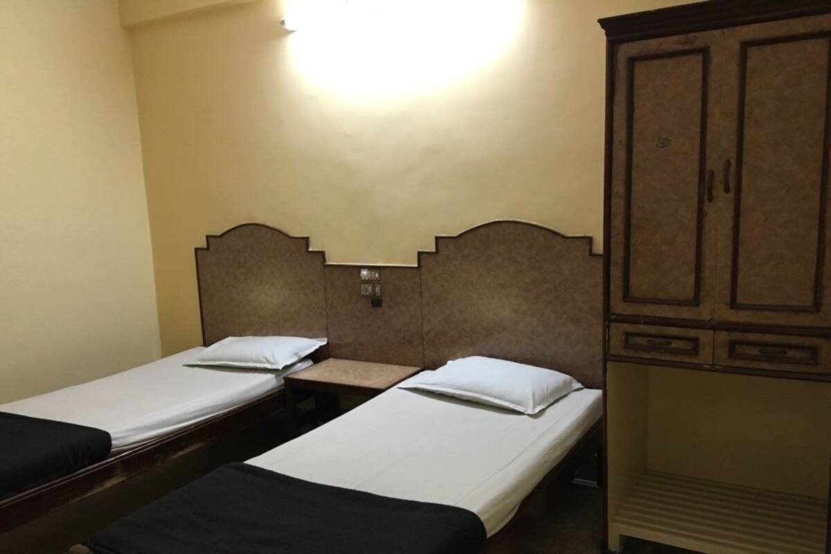 Ein Zimmer mit zwei Einzelbetten, einem Holzschrank und einem Nachttisch.