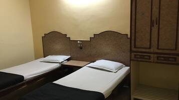 A room with two single beds, a wooden wardrobe, and a nightstand.