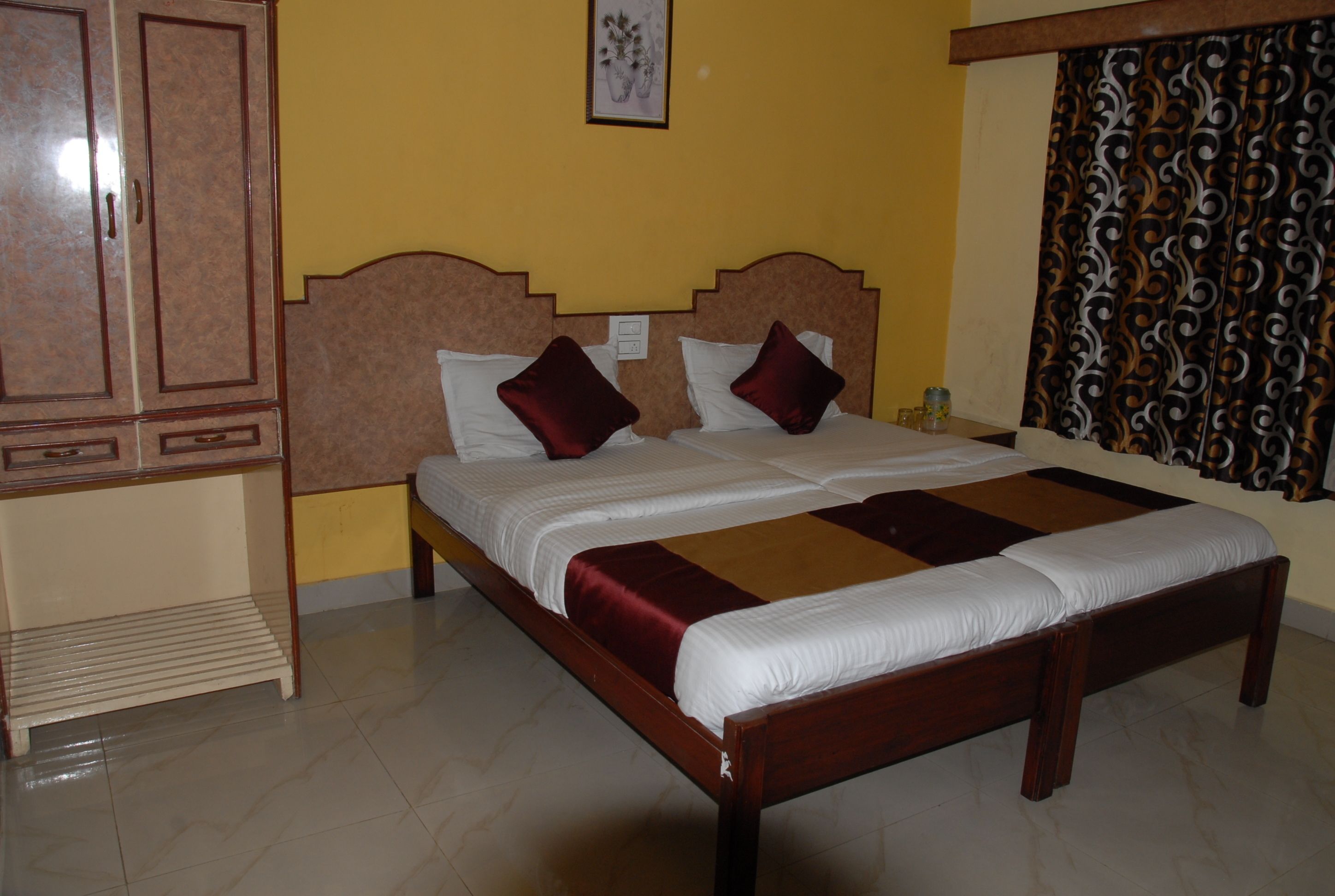 A double bed with a wooden frame and two red pillows, a bedside table, and a wardrobe.