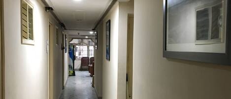 A hallway with marble flooring, framed pictures on the walls, and a door at the end.