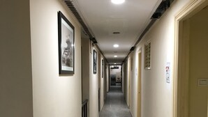 Ein langer, schmaler Korridor mit Marmorboden, Bilder an den Wänden und Türen auf beiden Seiten.