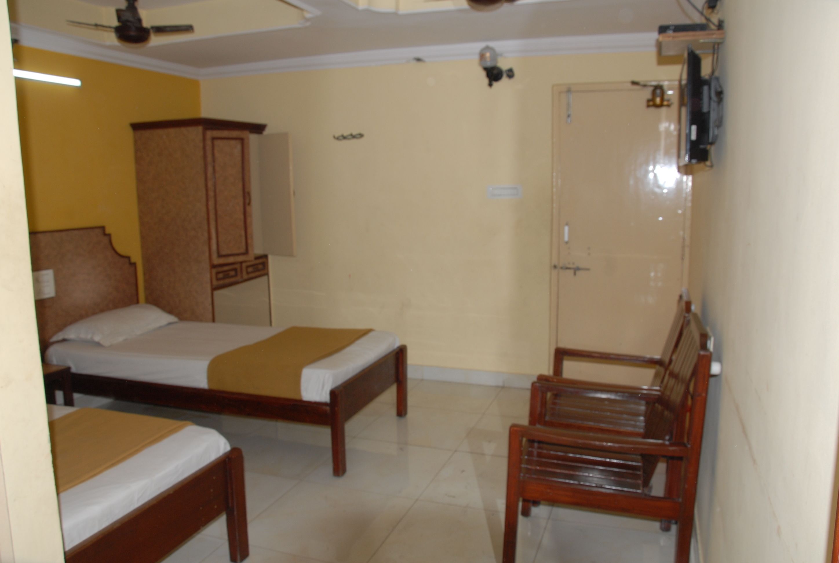 Una habitación con dos camas de madera, una silla de madera, un armario y una puerta.