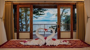 Una cama con vistas a un lago y montañas a través de un amplio ventanal.
