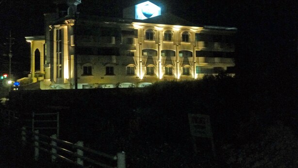 A building with multiple balconies and a central tower, illuminated at night. - Hotel Shalala (Okinawa)