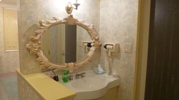 A bathroom with a large ornate mirror, a white sink, and a toilet.