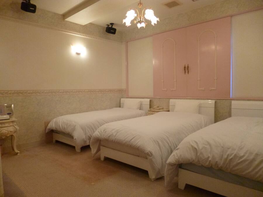 A hotel room with two single beds, a large mirror, and a chandelier.
