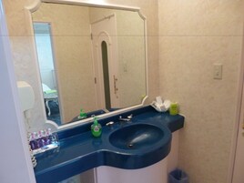 Un baño con lavamanos azul, un espejo y artículos de aseo en la encimera.