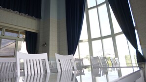 A room with large windows, white chairs, and a ceiling fan. - Hotel Shalala (Okinawa)